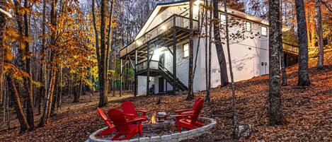 Une cabane dotée d’une terrasse, d’un foyer avec des sièges, et d’un escalier menant à l’étage supérieur.