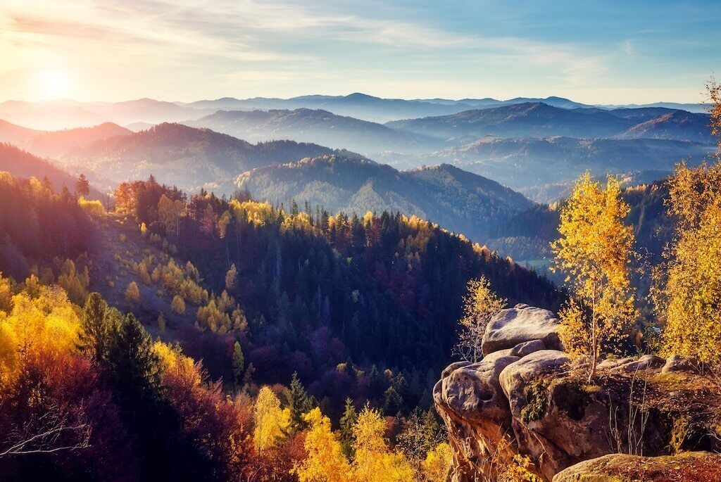 A mountainous landscape with autumn foliage and a prominent rock formation.