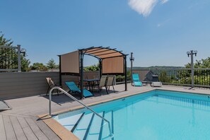 A swimming pool with a wooden deck, lounge chairs, a covered seating area, and a view of the landscape. - Newly Updated Condo w Gorgeous Table Rock View_Cmty Outdoor Pool_Near Sdc_Free Tickets (Branson)