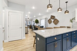 A modern kitchen with a large island, dark blue cabinets, and pendant lighting.