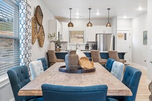 A modern kitchen with white cabinets, stainless steel appliances, and pendant lighting.