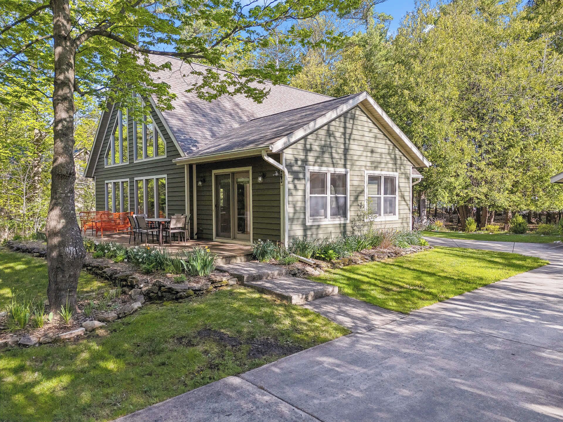 A single-story house with a porch, a small deck, and a well-maintained lawn.