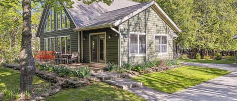 A single-story house with a porch, a small deck, and a well-maintained lawn.