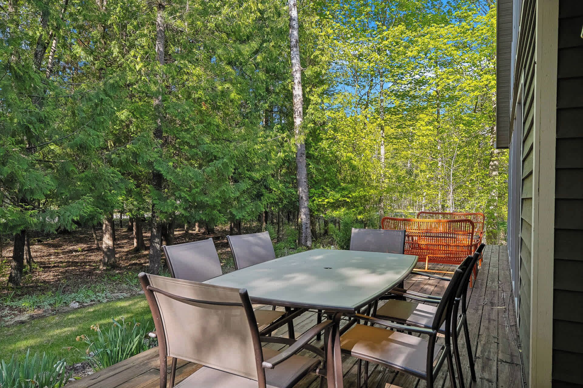 An outdoor patio with a table and chairs, surrounded by trees.
