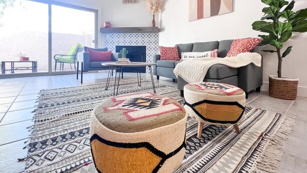 A living room with a sofa, ottomans, a coffee table, and a fireplace. - Southwestern Serene Oasis located in Chandler, featuring a community pool
 (Chandler)