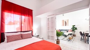 A bedroom with a large bed, a red curtain, and a view of an outdoor seating area with a table and chairs. - Southwestern Serene Oasis located in Chandler, featuring a community pool
 (Chandler)