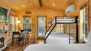 A wooden cabin interior with a bunk bed, a dining table with chairs, a fireplace, and a view through a door. - Mt Lemmon Hotel Summerhaven Cabin 12 (Mount Lemmon)
