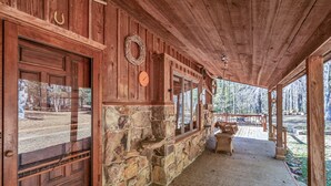Una baita in legno con fondamenta in pietra, grandi porte di legno e un portico con mobili in vimini.