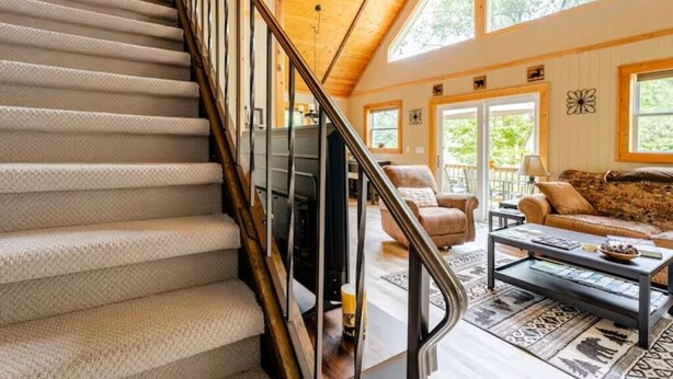 A staircase leading to a living area with a fireplace, a sofa, and a coffee table. - Cozy Chalet in the Heart of Northern Michigan (Williamsburg)