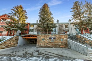 A hotel entrance with a stone wall, a sign reading 'Snow Flower,' and a staircase leading to the building. - Modern home with three balconies, mountain views, and outdoor swimming pool. Walk to hiking trails (Park City)
