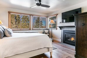 A bedroom with a bed, a fireplace, and a TV mounted above it. - Modern home with three balconies, mountain views, and outdoor swimming pool. Walk to hiking trails (Park City)