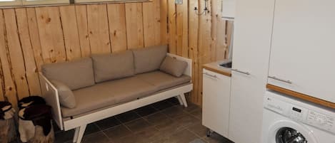 A compact room with a sofa, a washing machine, and a window.