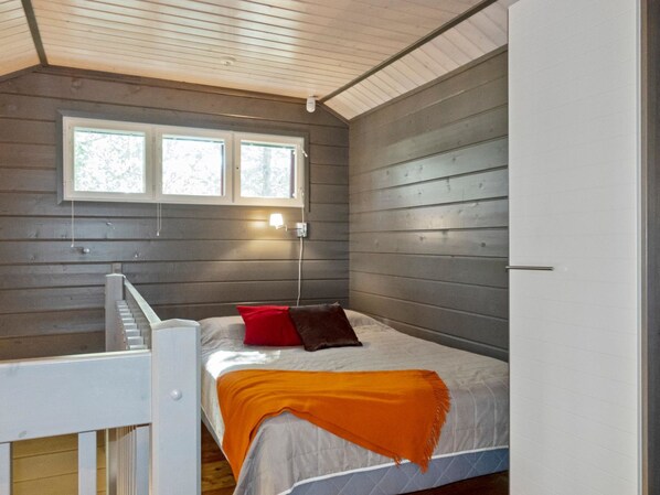 A bedroom with a bed, a window, and a staircase.