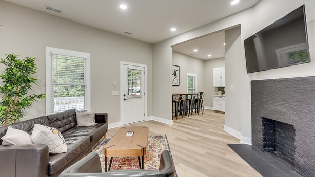 A modern living room with a leather sofa, a wooden coffee table, and a fireplace. - 4 Bedroom Home Close to Everything (Atlanta)