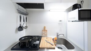 A modern kitchen with white cabinets, a gas stove, a microwave, and a sink.