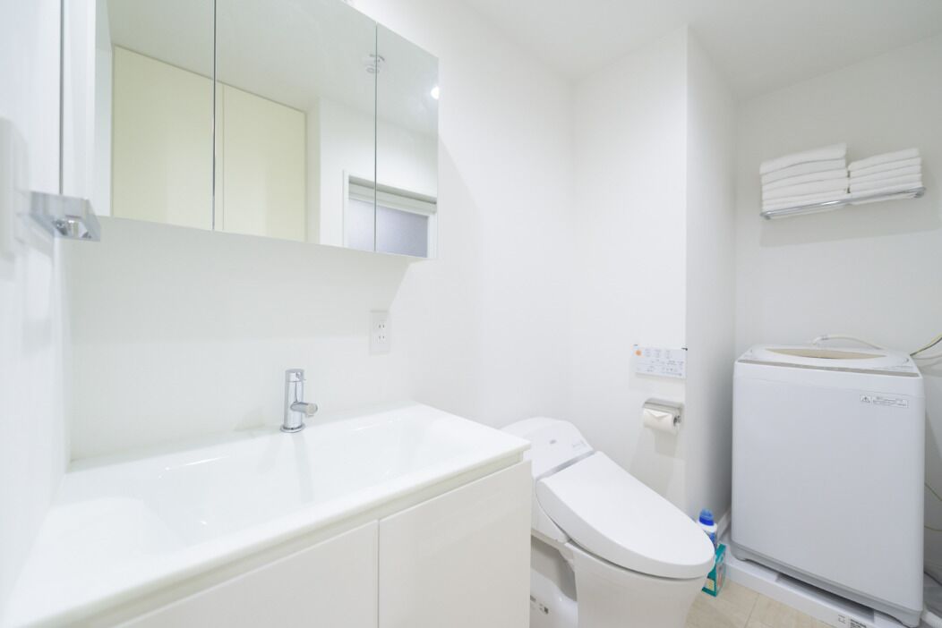 A modern bathroom with a white sink, toilet, and a built-in washing machine.