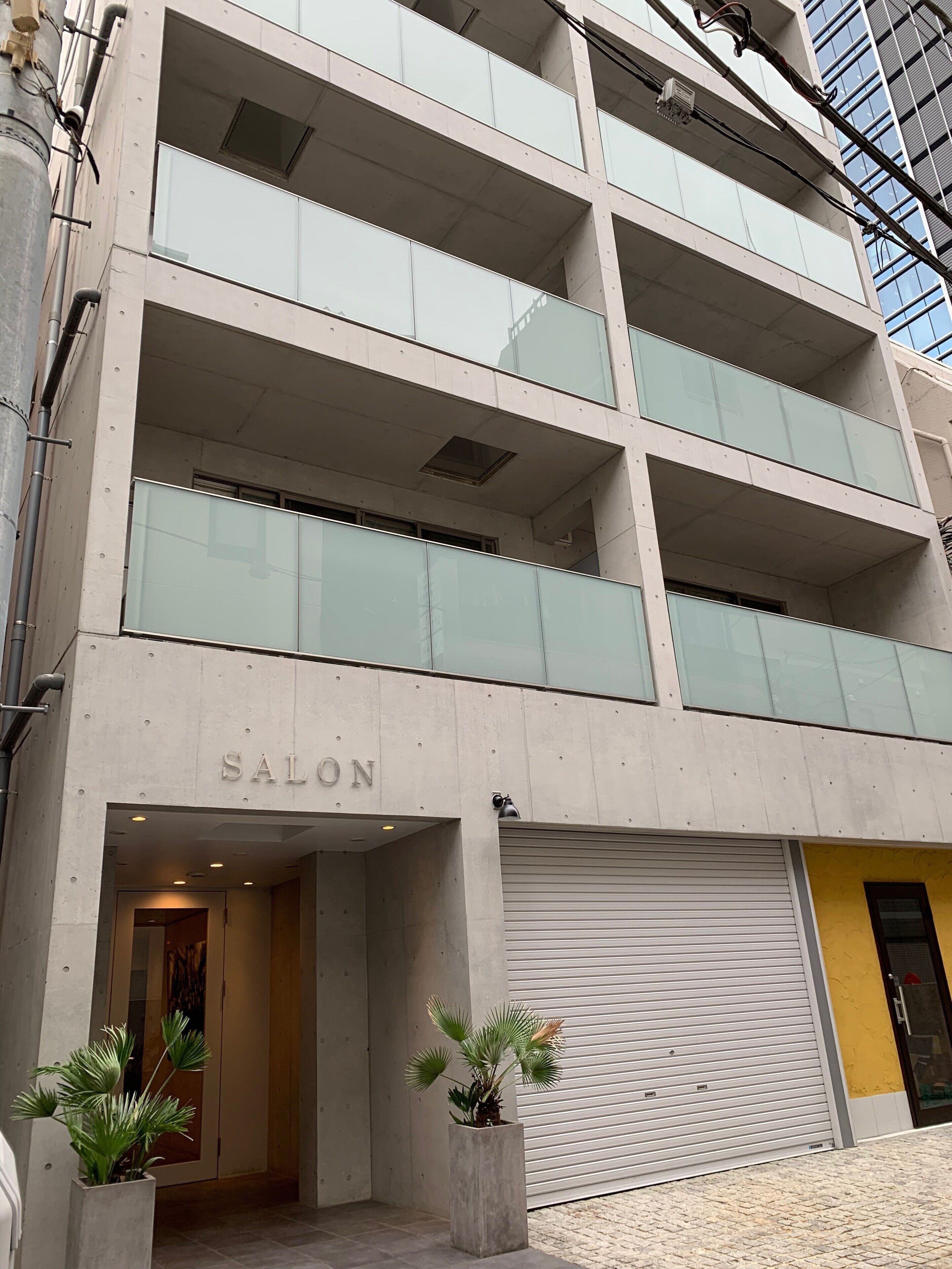 A modern building with a 'SALON' sign, large windows, and a closed garage door.
