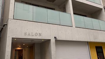 A modern building with a 'SALON' sign, large windows, and a closed garage door.