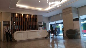 A modern lobby with a reception desk, a security officer, and a seating area. - The SCENIC: Comfortable living by Awsom Phil (Manila)