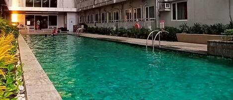 A swimming pool with a tiled edge, surrounded by a stone border and a pebble bed.