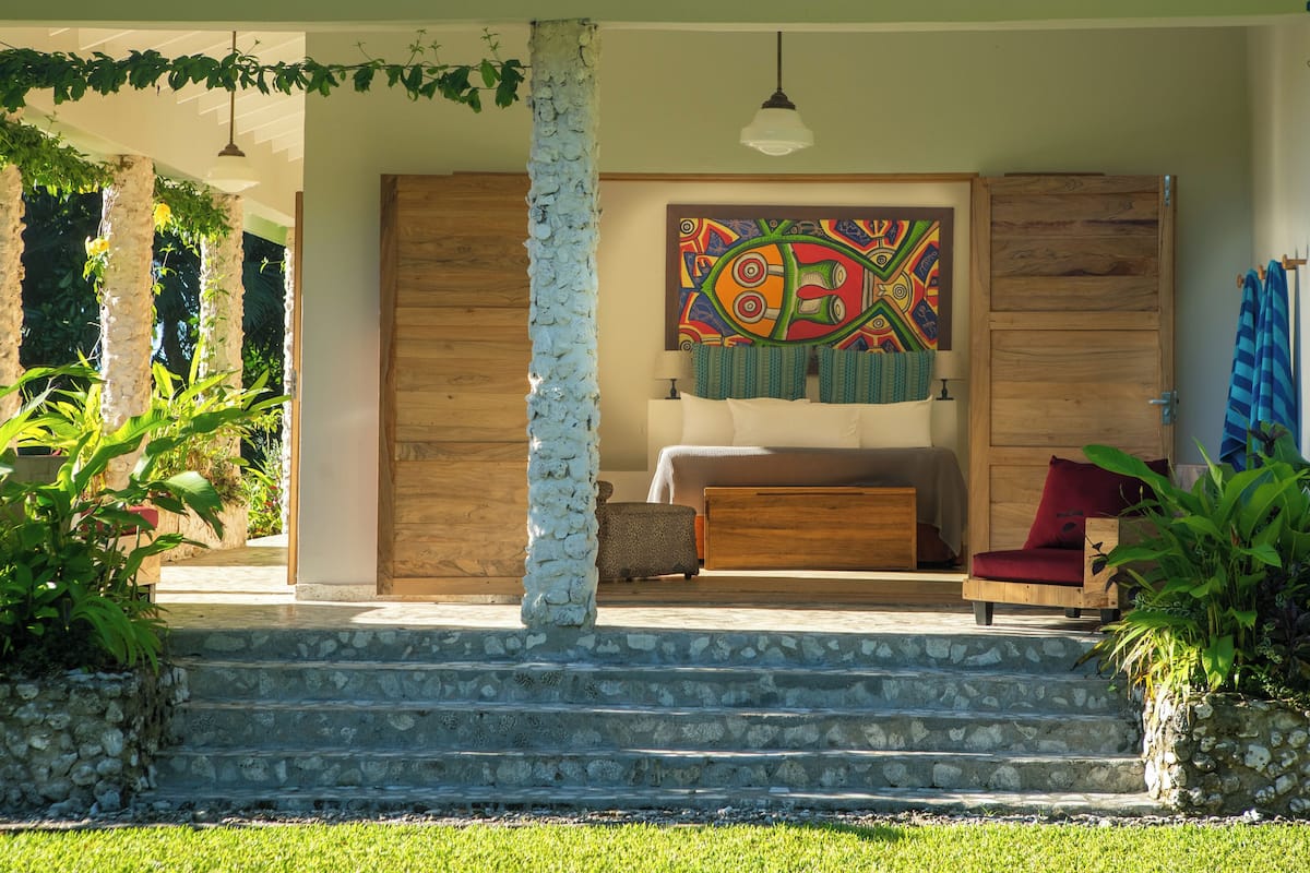 Quarto com cama, uma obra de arte colorida e uma cadeira vermelha.