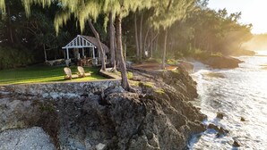A coastal property with a gazebo, chairs, and a view of the ocean. - Nakatumble (Mele)