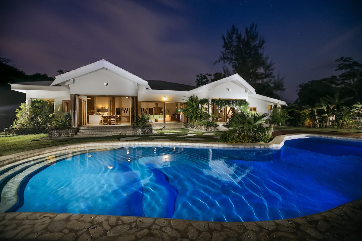 Uma casa moderna com piscina, varanda coberta e um jardim bem cuidado.