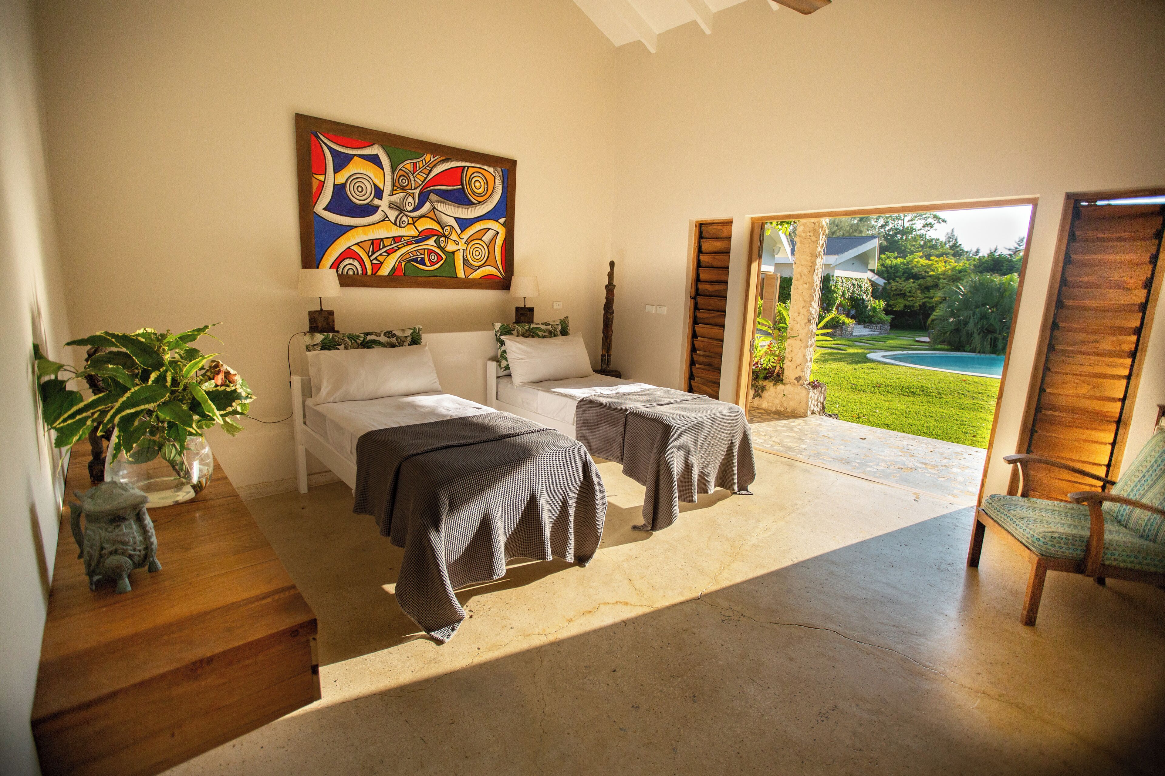 Un dormitorio con dos camas, un cuadro grande y vistas a un jardín y una piscina.