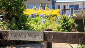 Une pancarte en bois portant l’inscription « Whalers Watch » est fixée à une clôture en bois.
