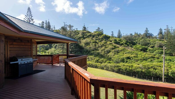 A wooden deck with a barbecue, a covered area, and a view of a forested hillside. - Tranquility at Cascade (Norfolk Island)