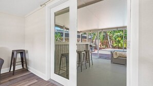 A room with a sliding glass door leading to an outdoor area with a bar and seating.