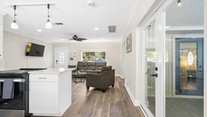 A modern kitchen with a built-in oven, a dining area with a glass table, and a seating area with a sofa.