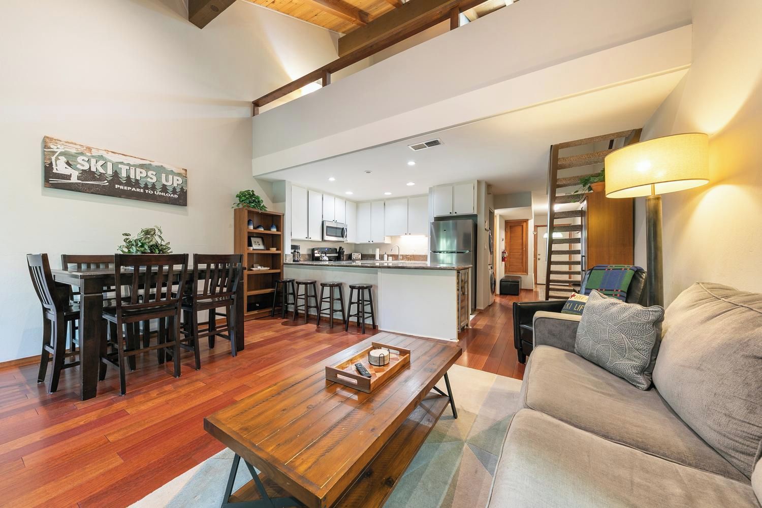 A spacious living area with a wooden coffee table, a sofa, and a dining table with chairs.