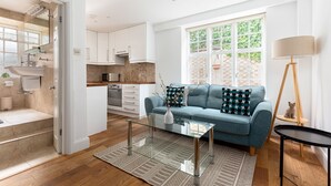 A modern kitchen with white cabinets, a built-in oven, and a window with a view of greenery. - The St Johns Wood Apartment (London)