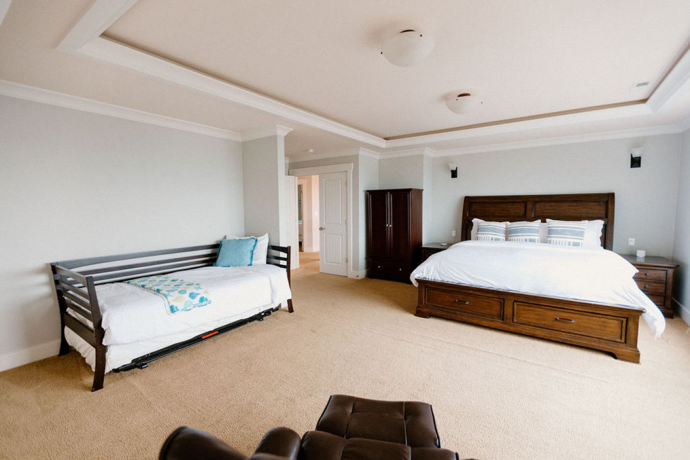 A bedroom with a large bed, a wooden bench, and a wardrobe.