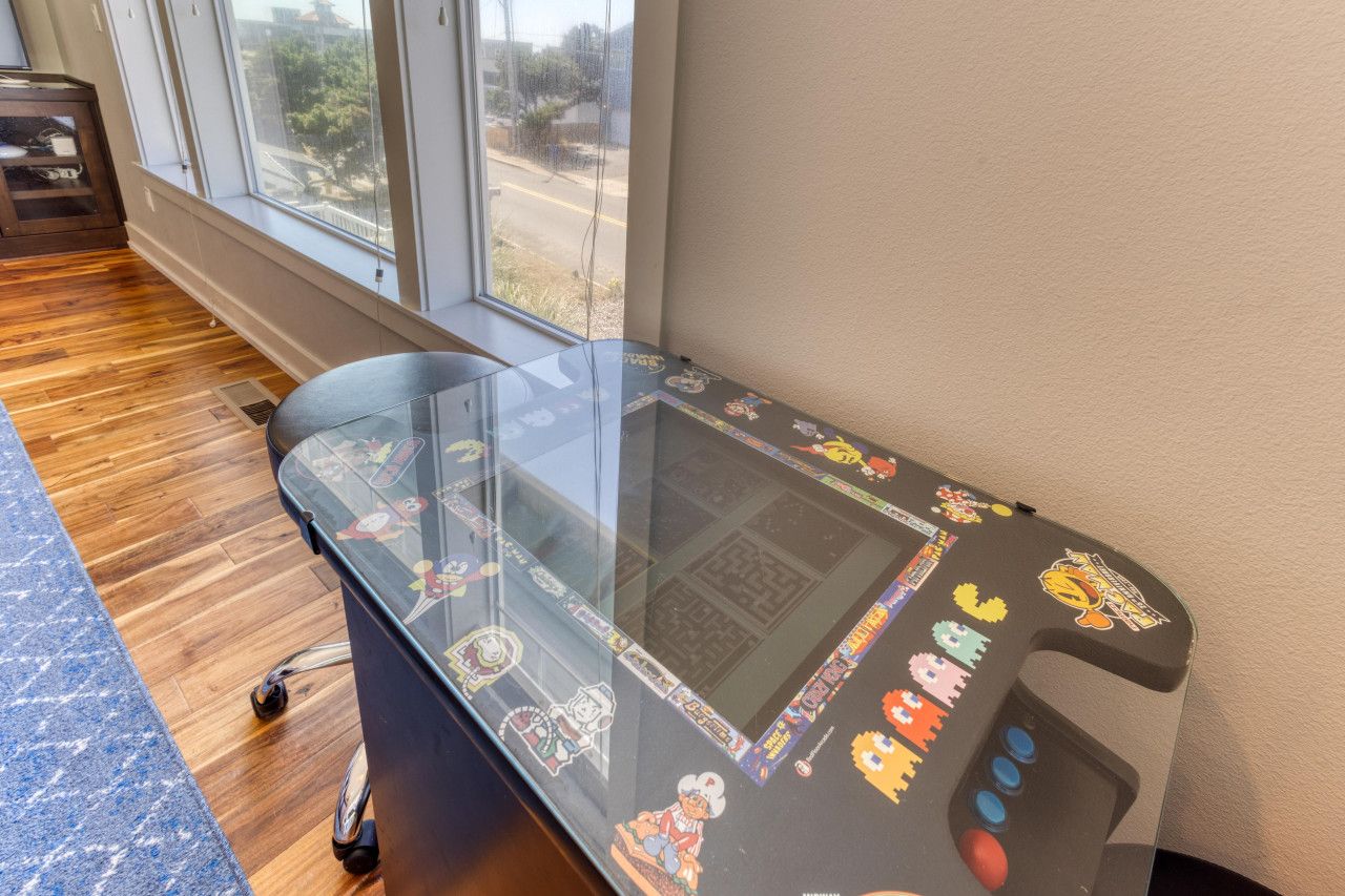 Een glazen tafel met een gamecontroller, een raam met uitzicht op de straat en een houten vloer.