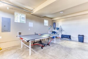 A ping pong table in a room with a concrete floor, a door, and windows.