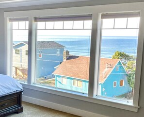 Un dormitorio con un amplio ventanal con vistas a una playa y casas.