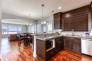 A modern kitchen with a large island, dark wood cabinets, and a view to the outside.