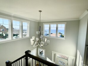 A spacious room with large windows, a chandelier, and a view of the ocean.