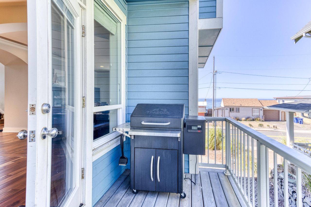 Un balcon équipé d’un barbecue, d’un petit meuble de rangement et d’une porte donnant sur l’intérieur.