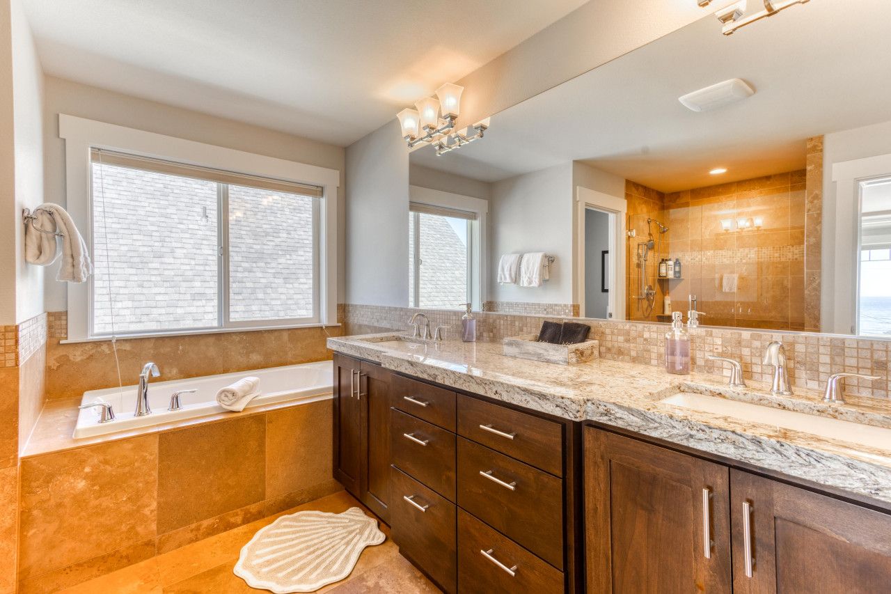 A bathroom with a large mirror, a bathtub, and a vanity with a sink.