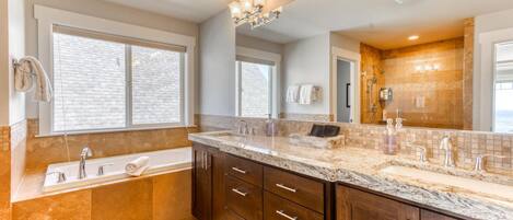 A bathroom with a large mirror, a bathtub, and a vanity with a sink.