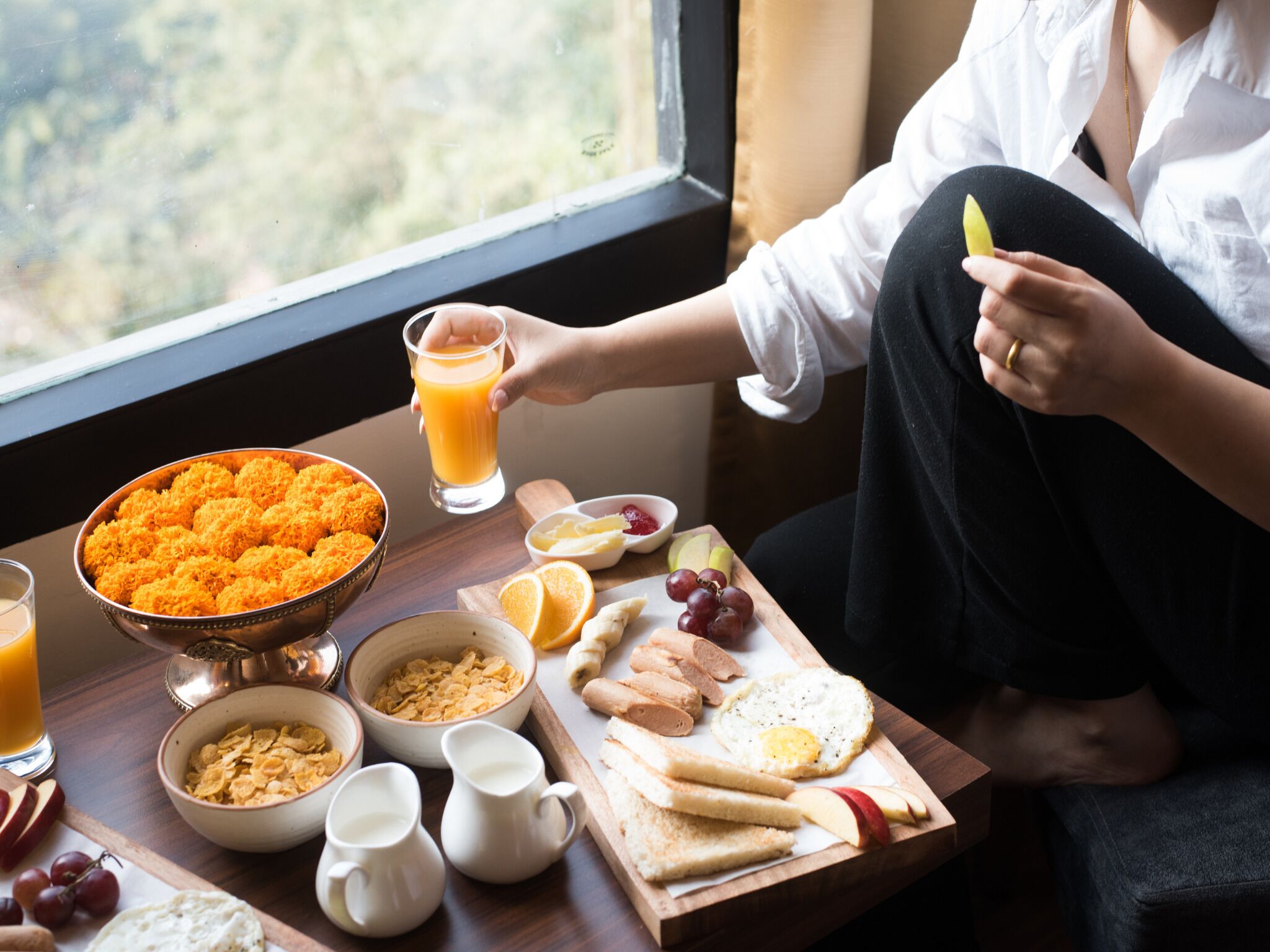 A breakfast table with various food items and a glass of orange juice.