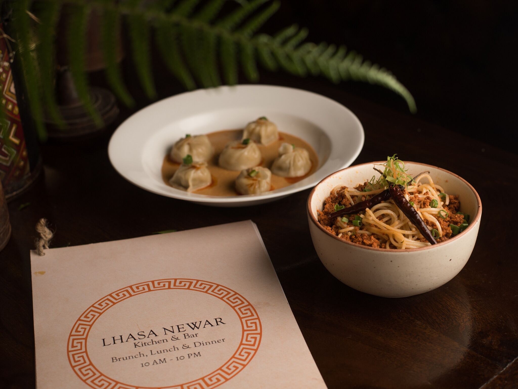 A menu with the name "Lhasa Newar" and mentions "Kitchen & Bar" and "Brunch, Lunch & Dinner" from 10 AM to 10 PM.