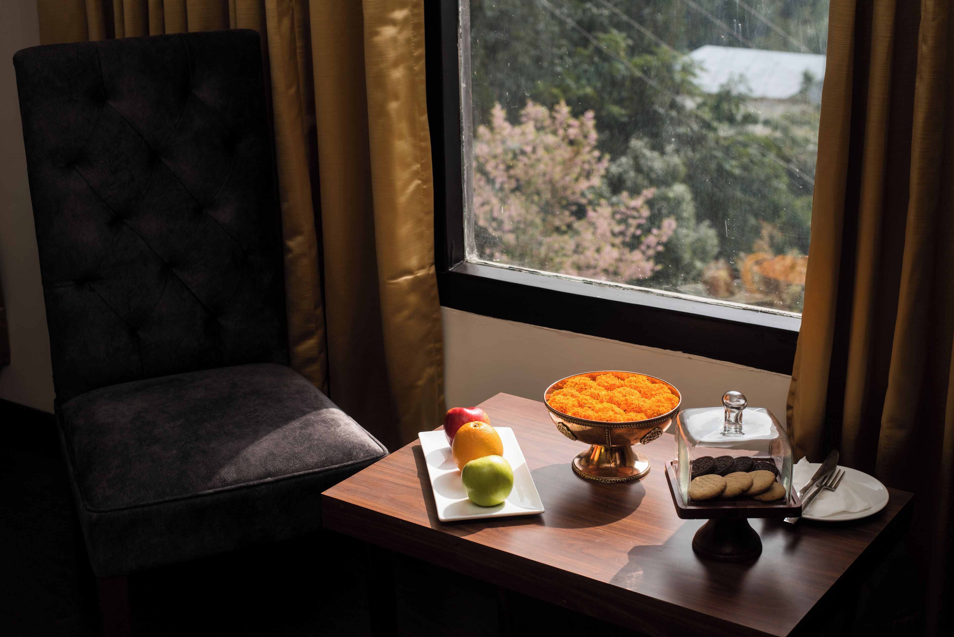 A dining table with a fruit plate, a bowl of carrots, and a cookie display.