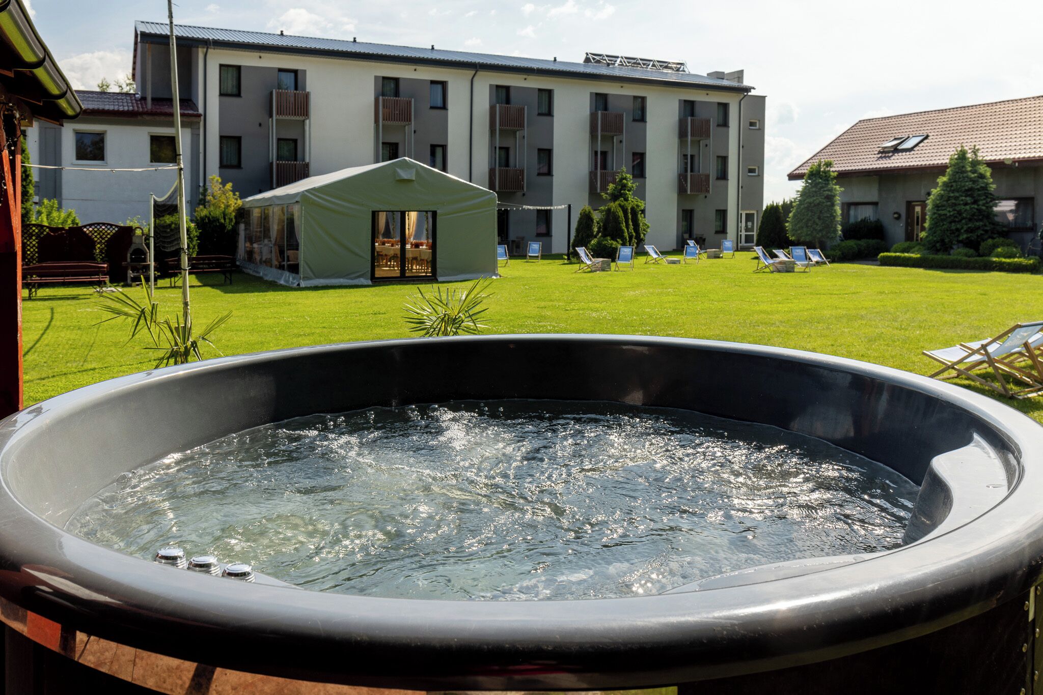 Un jacuzzi dans un jardin, avec un bâtiment visible à l’arrière-plan.