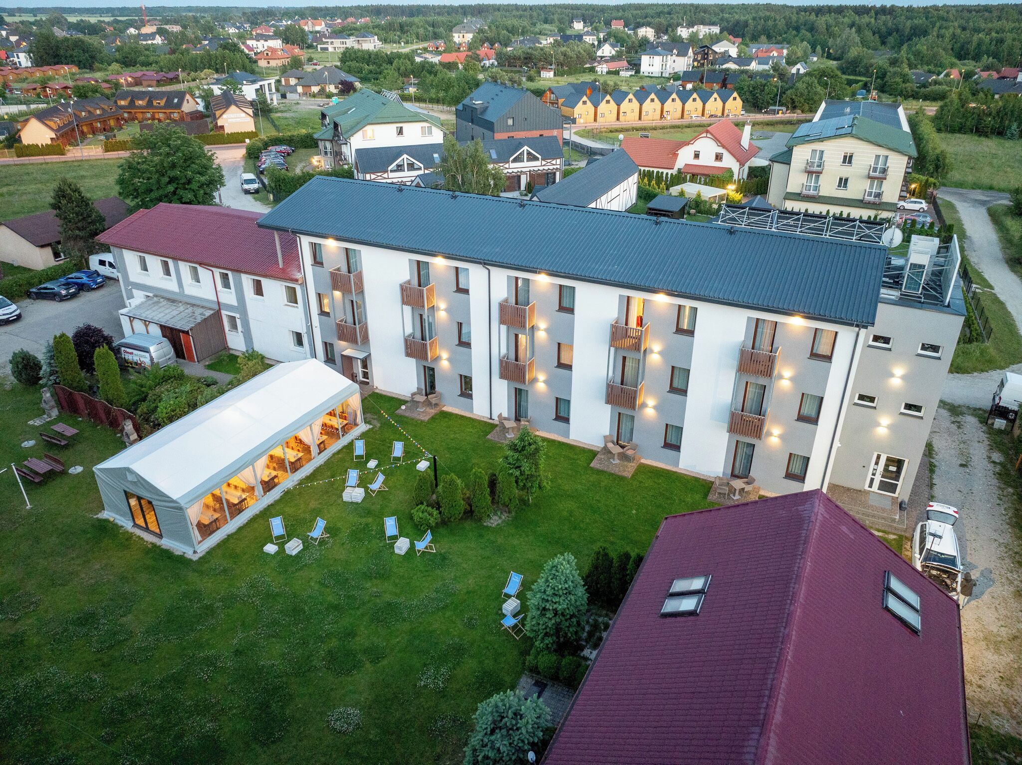 Un hotel de varios pisos con un patio central, zona de estar al aire libre y aparcamiento.