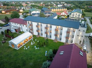 A multi-story hotel with a central courtyard, outdoor seating area, and a parking lot.