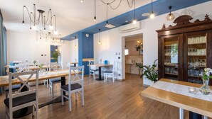 A modern dining area with wooden tables and chairs, hanging pendant lights, and a wooden cabinet with glassware. - Awilla (Ustka)